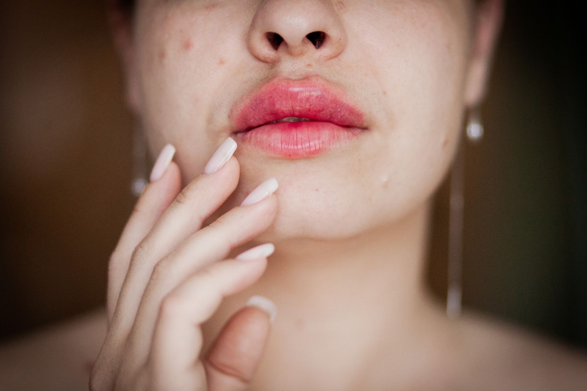 Ejercicios faciales para los labios: fotografía editorial de a woman touching her lips