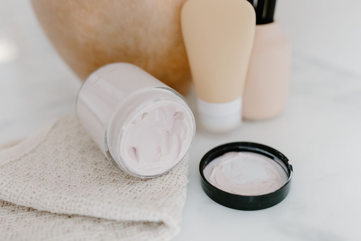 Crema hidratante vs crema antiedad: fotografía editorial de tarro de crema facial y productos cosméticos de cuidado