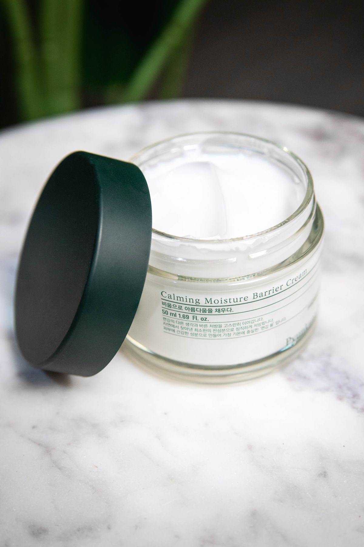 Los ingredientes con mejor evidencia para las arrugas: fotografía editorial de tarro abierto de crema cosmética para el cuidado facial