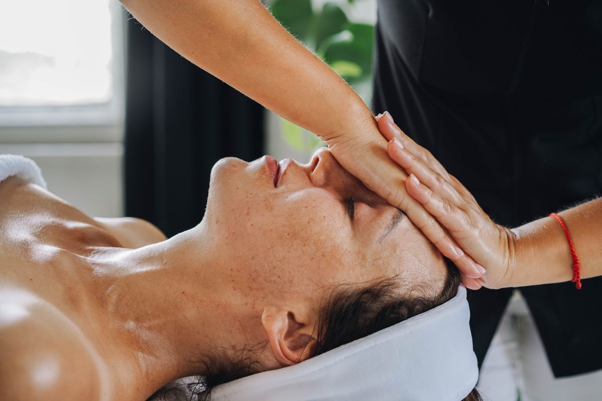 Masaje para las ojeras: fotografía editorial de manos realizando un masaje facial calmante en una sesión de cuidado